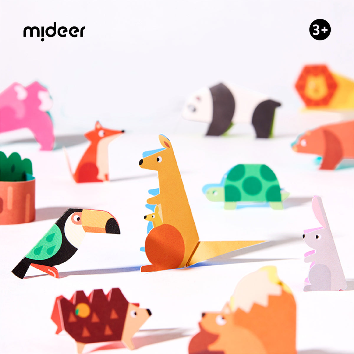 A set of colorful, animal-shaped origami paper toys arranged on a white surface with soft shadows. The set includes a kangaroo, toucan, rabbit, turtle, fox, hedgehog, lion, and other safari animals in bright, playful colors.
