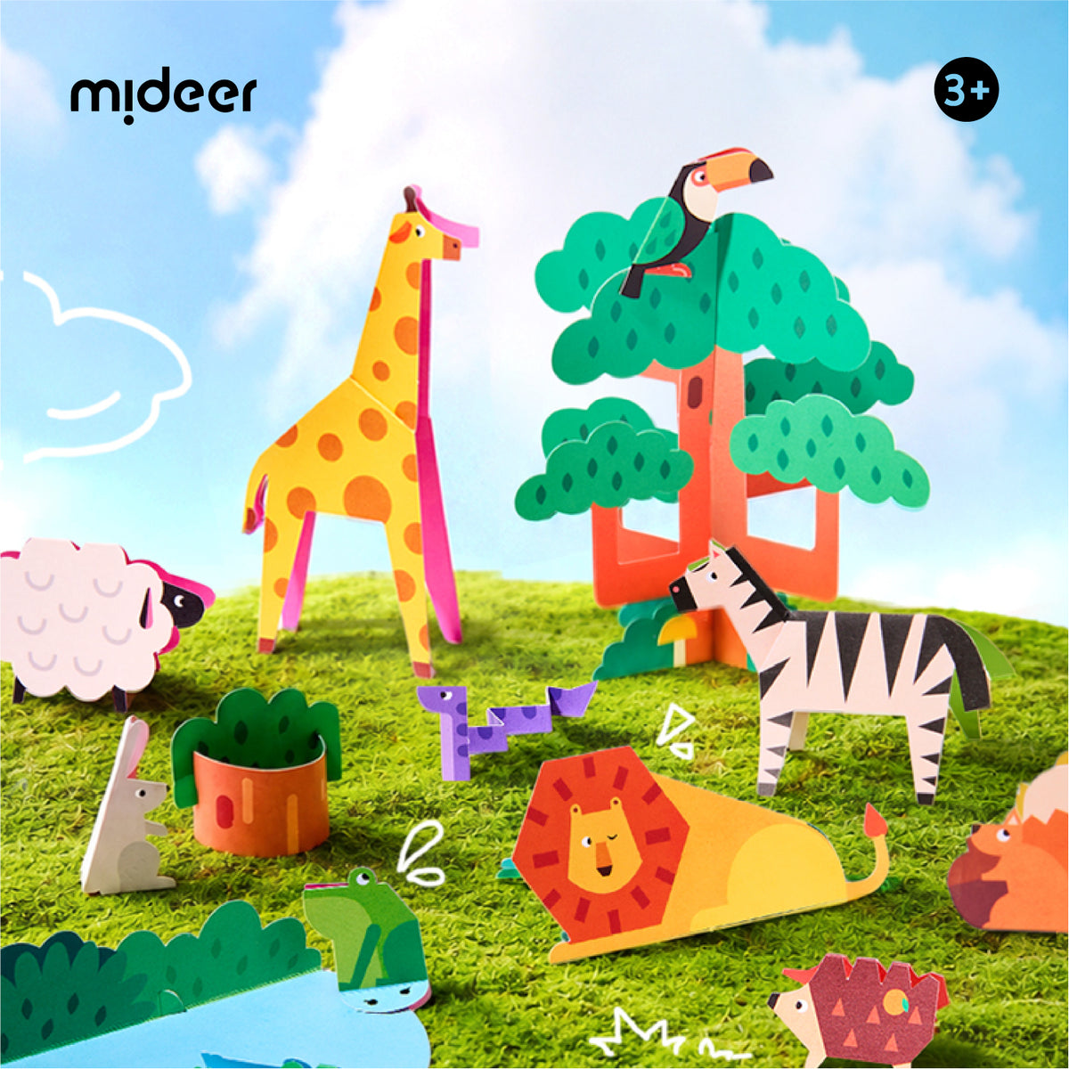 A colorful children's cardboard animal and nature building set by mIDEER, featuring assembled paper animals including a giraffe, zebra, lion, toucan, sheep, frog, and hedgehog on a grassy hill under a blue sky with clouds.